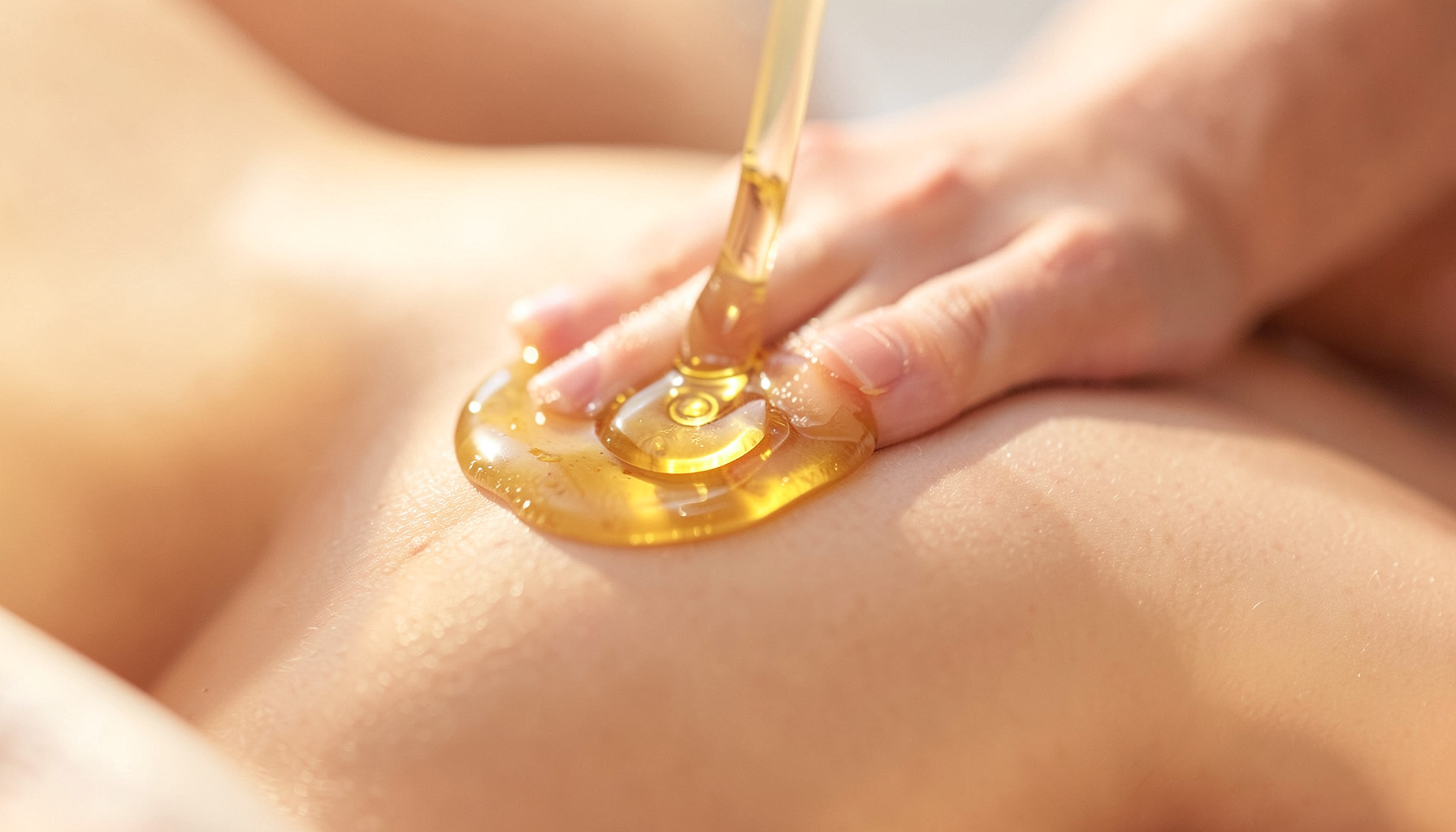 Warm golden oil being gently massaged onto smooth skin in soft natural light, conveying self-care and nourishment